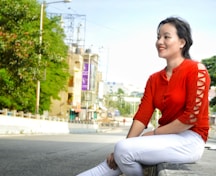 a woman in a red shirt is sitting on a bench