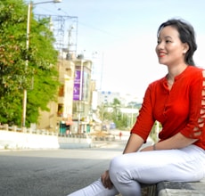 a woman in a red shirt is sitting on a bench