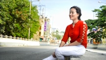 a woman in a red shirt is sitting on a bench