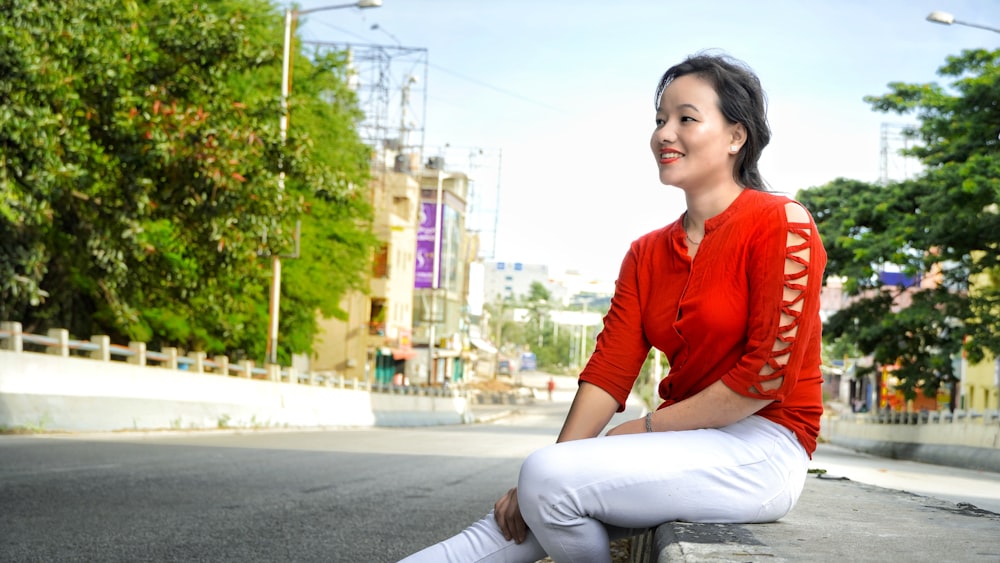 a woman in a red shirt is sitting on a bench