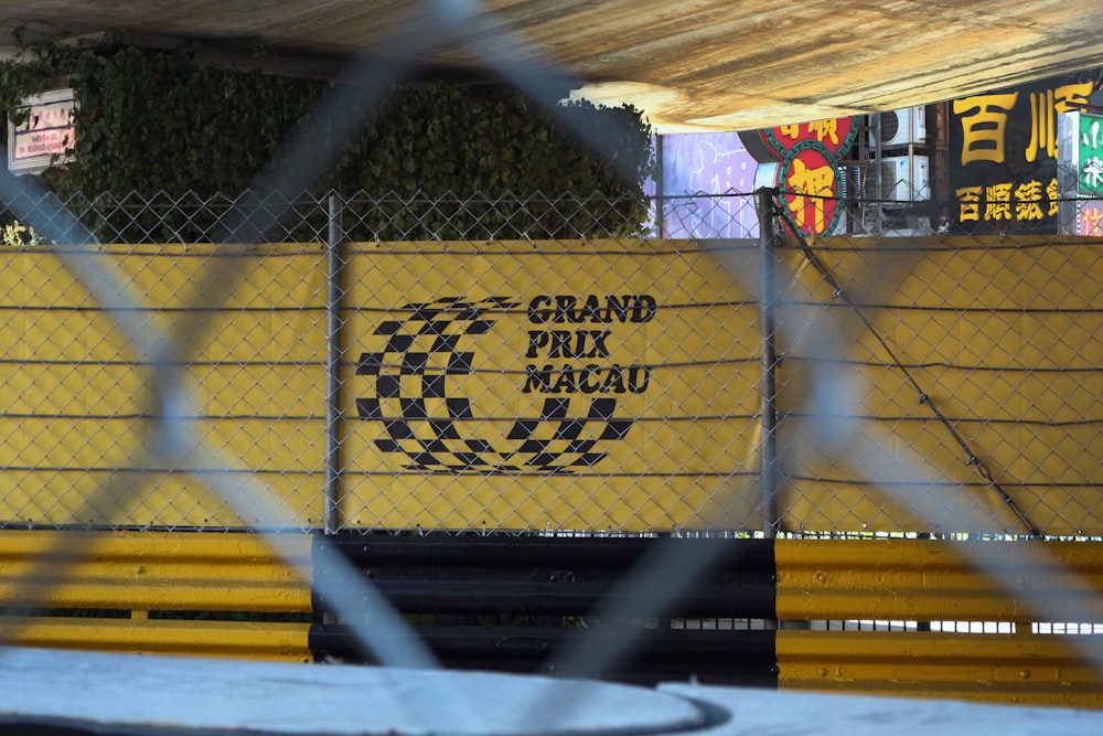 a yellow and black sign behind a chain link fence