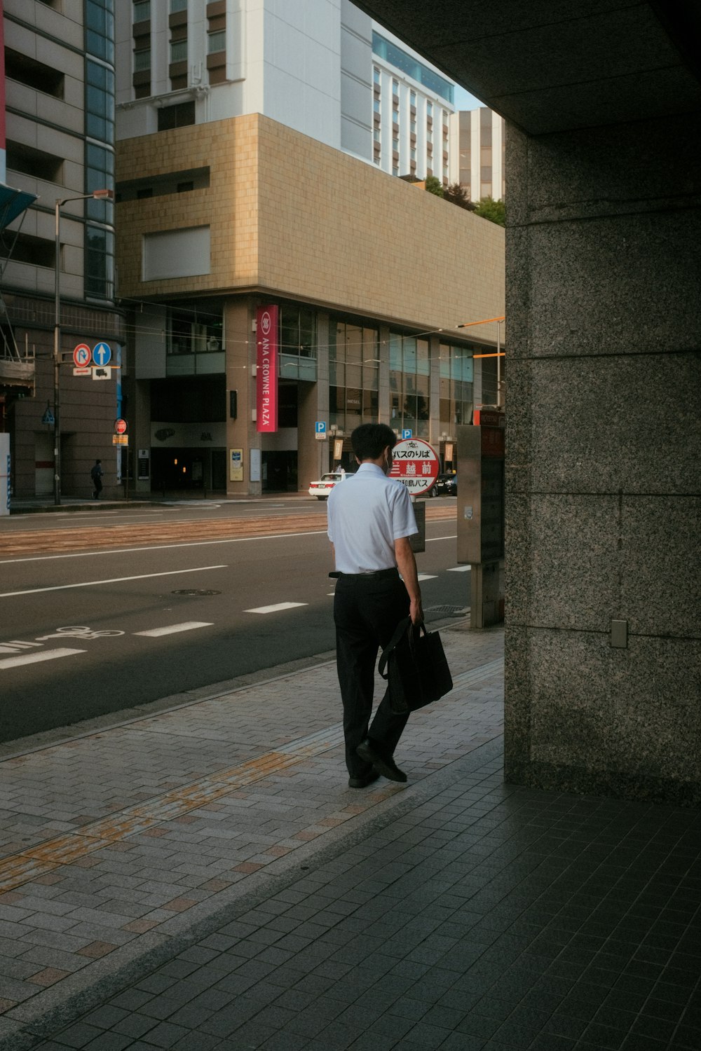 a man walking down a sidewalk carrying a briefcase