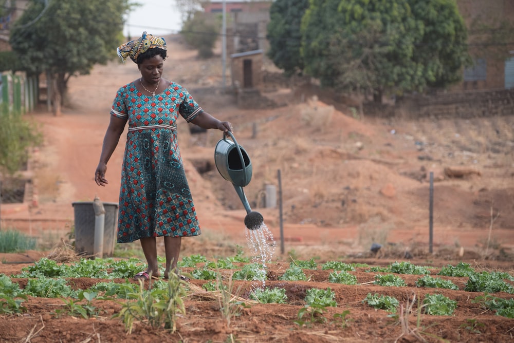a woman watering her garden with a watering can