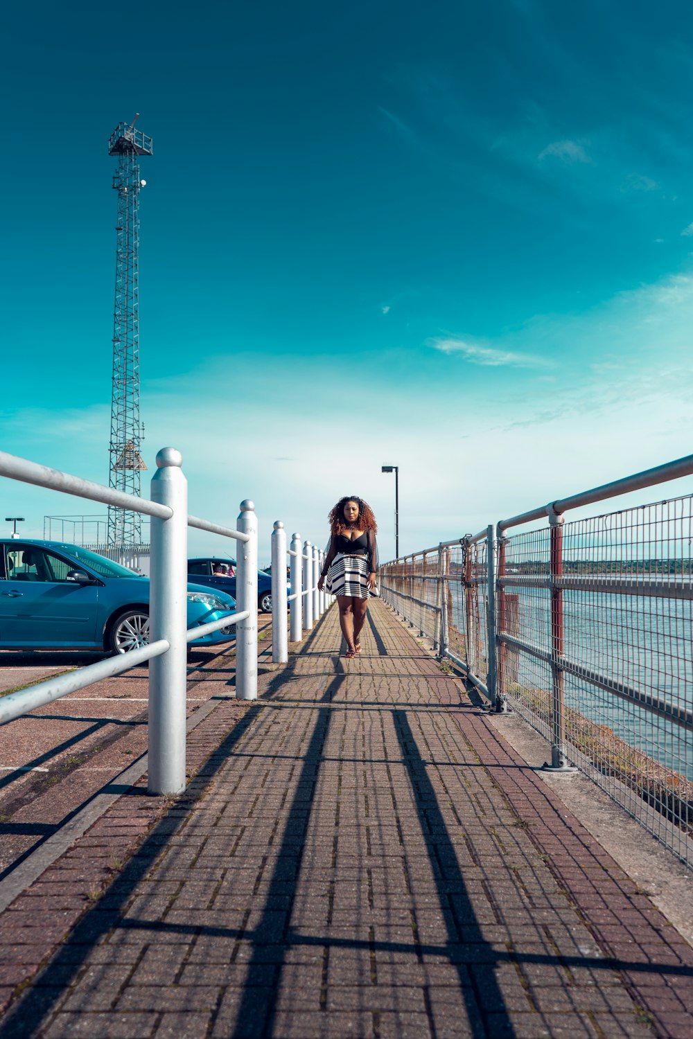 a woman walking down a sidewalk next to the ocean