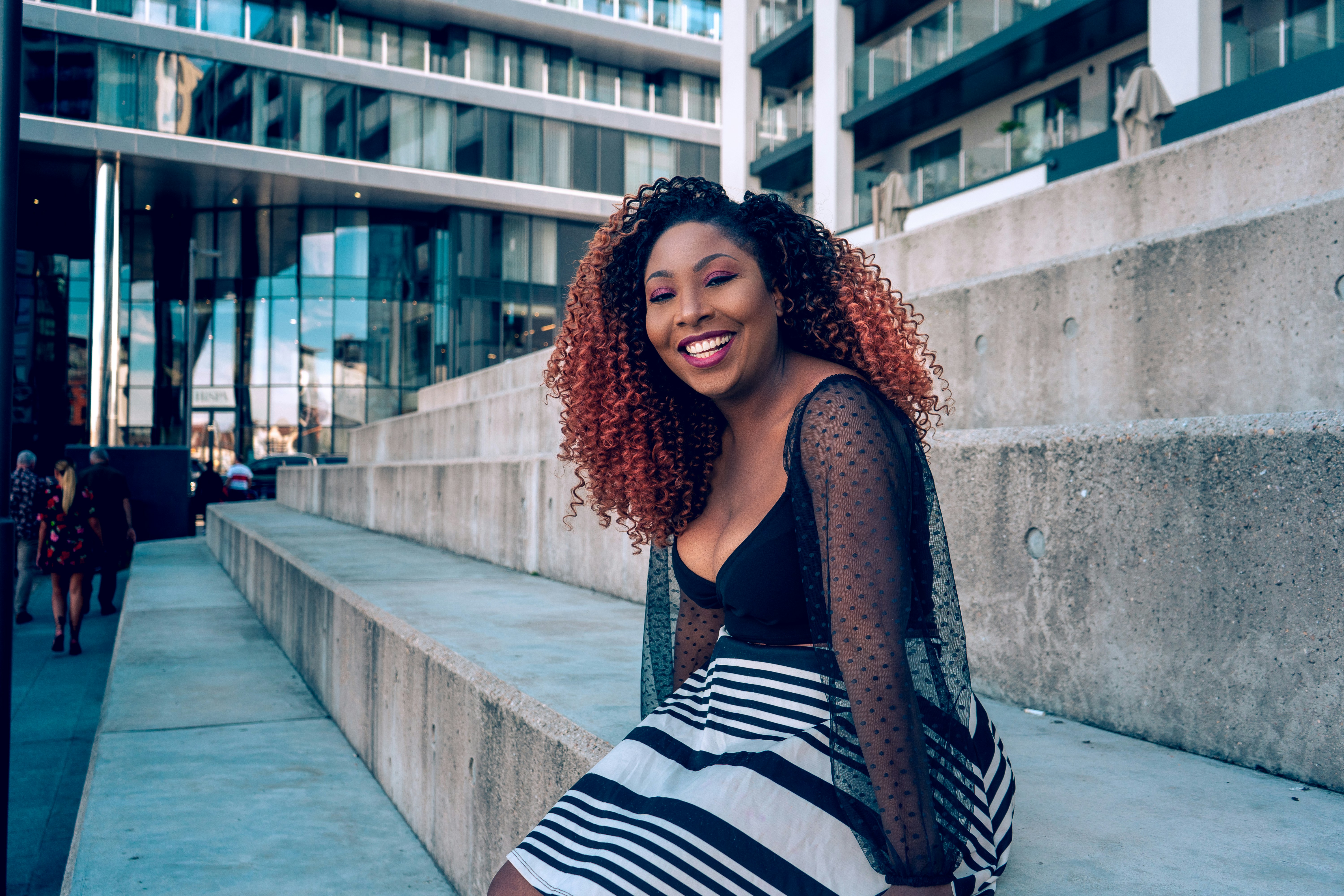Une femme aux cheveux roux est assise sur quelques marches