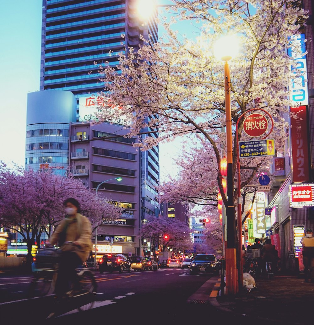 a man riding a bike down a street next to tall buildings