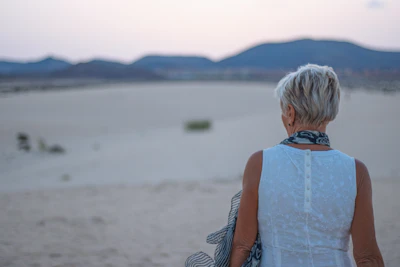 a woman standing in the sand with a scarf around her neck