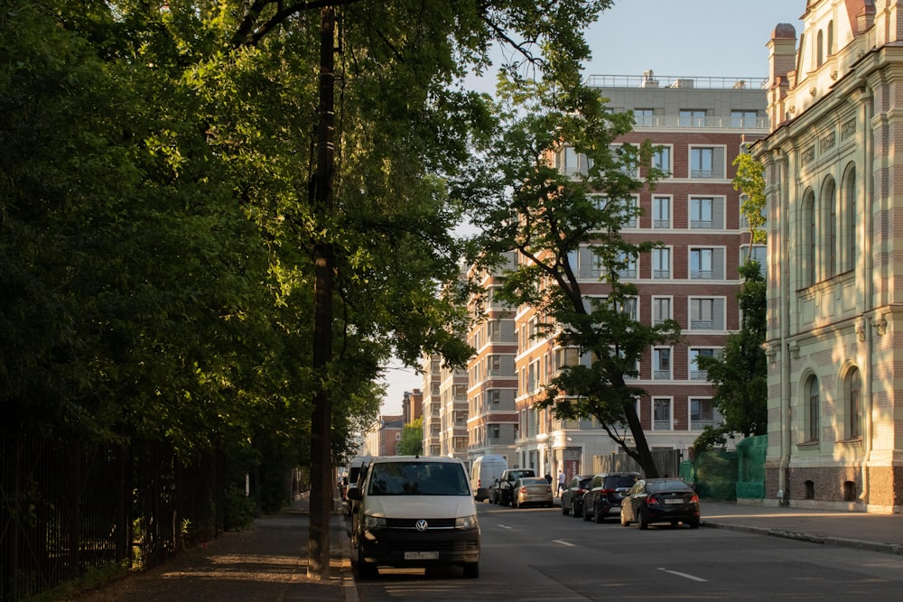 a city street lined with parked cars and tall buildings