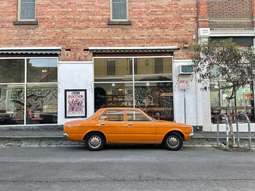 an orange car parked in front of a store