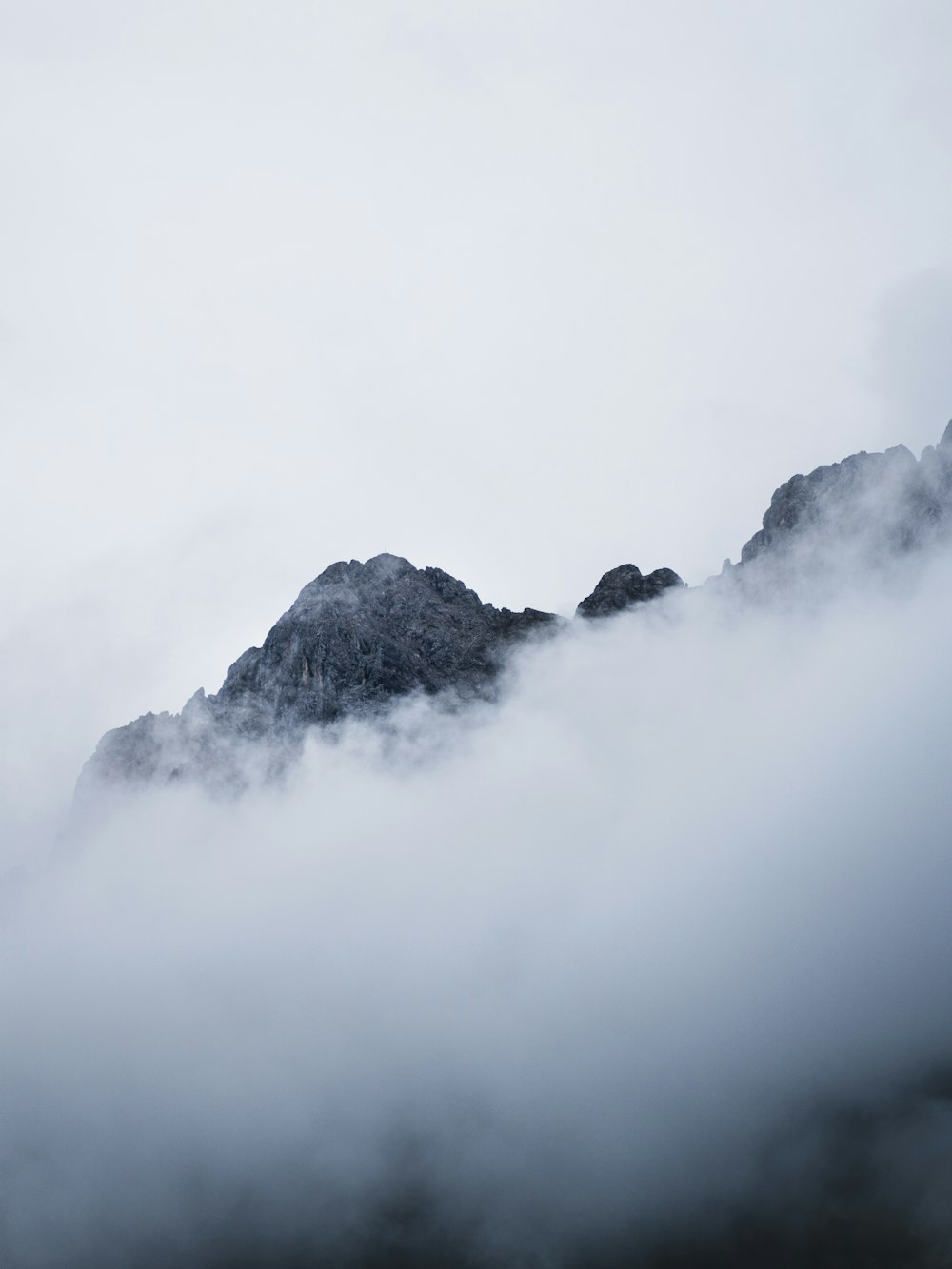 a mountain covered in fog and clouds on a cloudy day