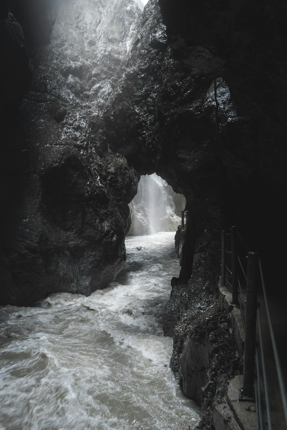 a river flowing under a bridge next to a cliff