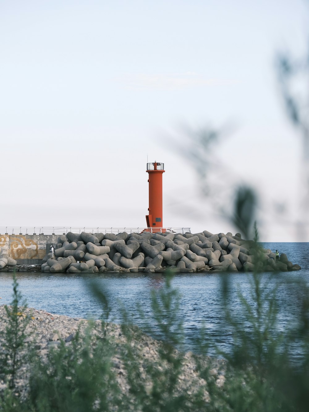 a red light house sitting on top of a rock wall