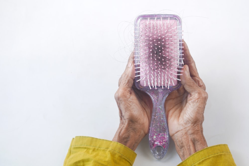 uma pessoa segurando uma escova de cabelo em suas mãos