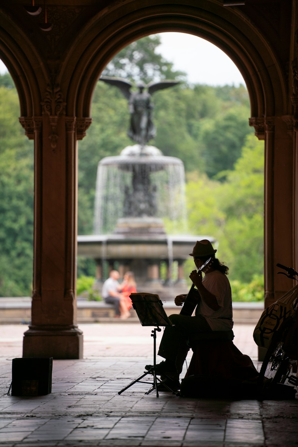 a person sitting on a bench in front of a fountain