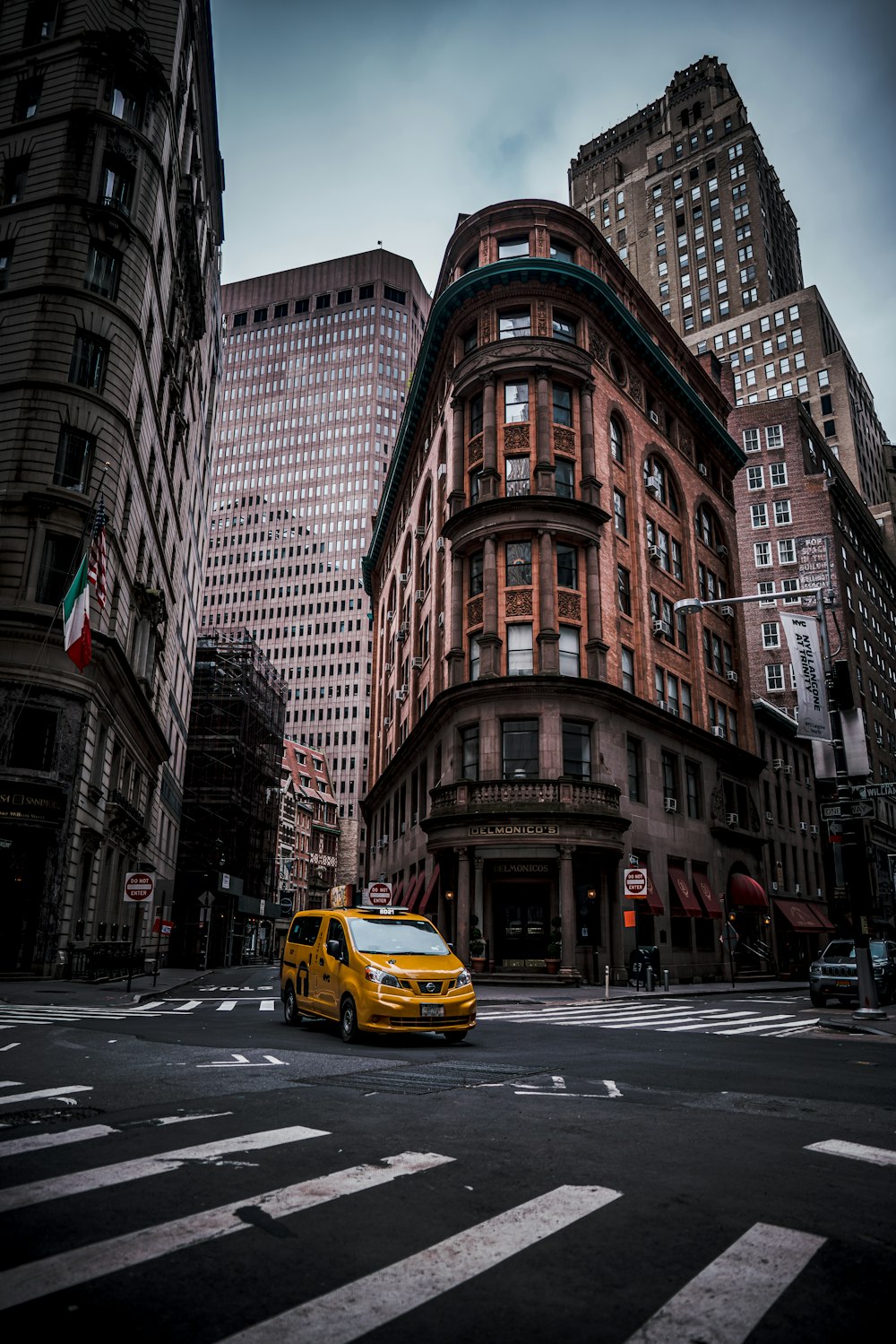 a yellow taxi cab driving down a street next to tall buildings