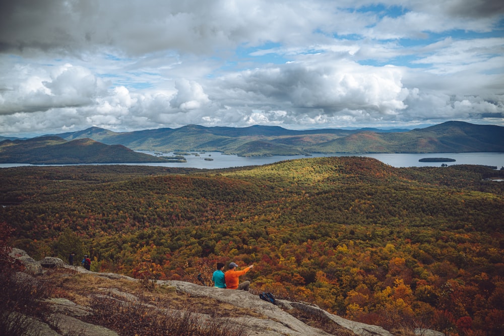 a couple of people sitting on top of a mountain