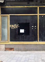 Exterior of a small storefront before improvements, with chipped paint and old signage.