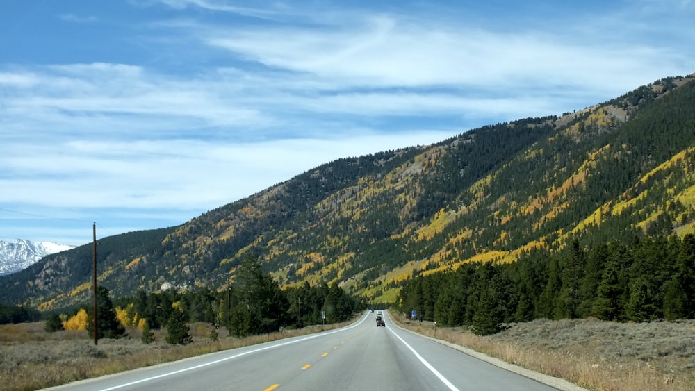 a car driving down a road with a mountain in the background