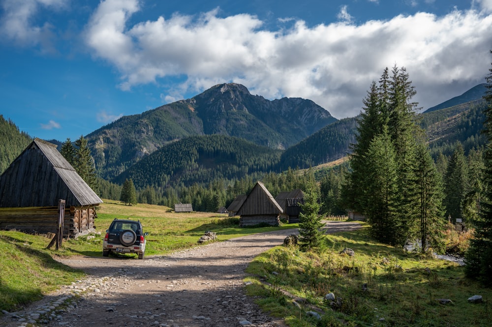 a car parked on a dirt road in front of a cabin