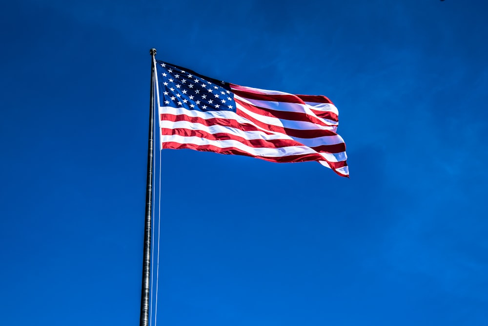 a large american flag flying in the blue sky