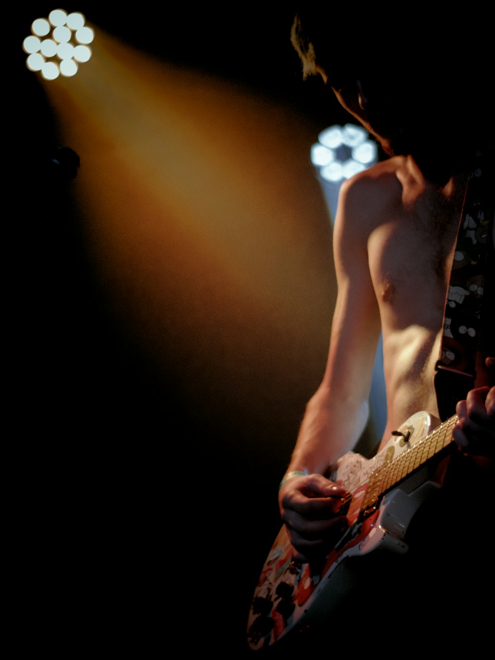 a shirtless man playing a guitar on stage