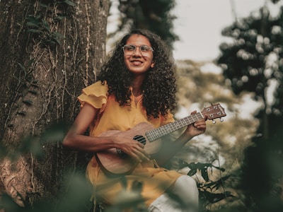 a woman in a yellow dress playing a ukulele