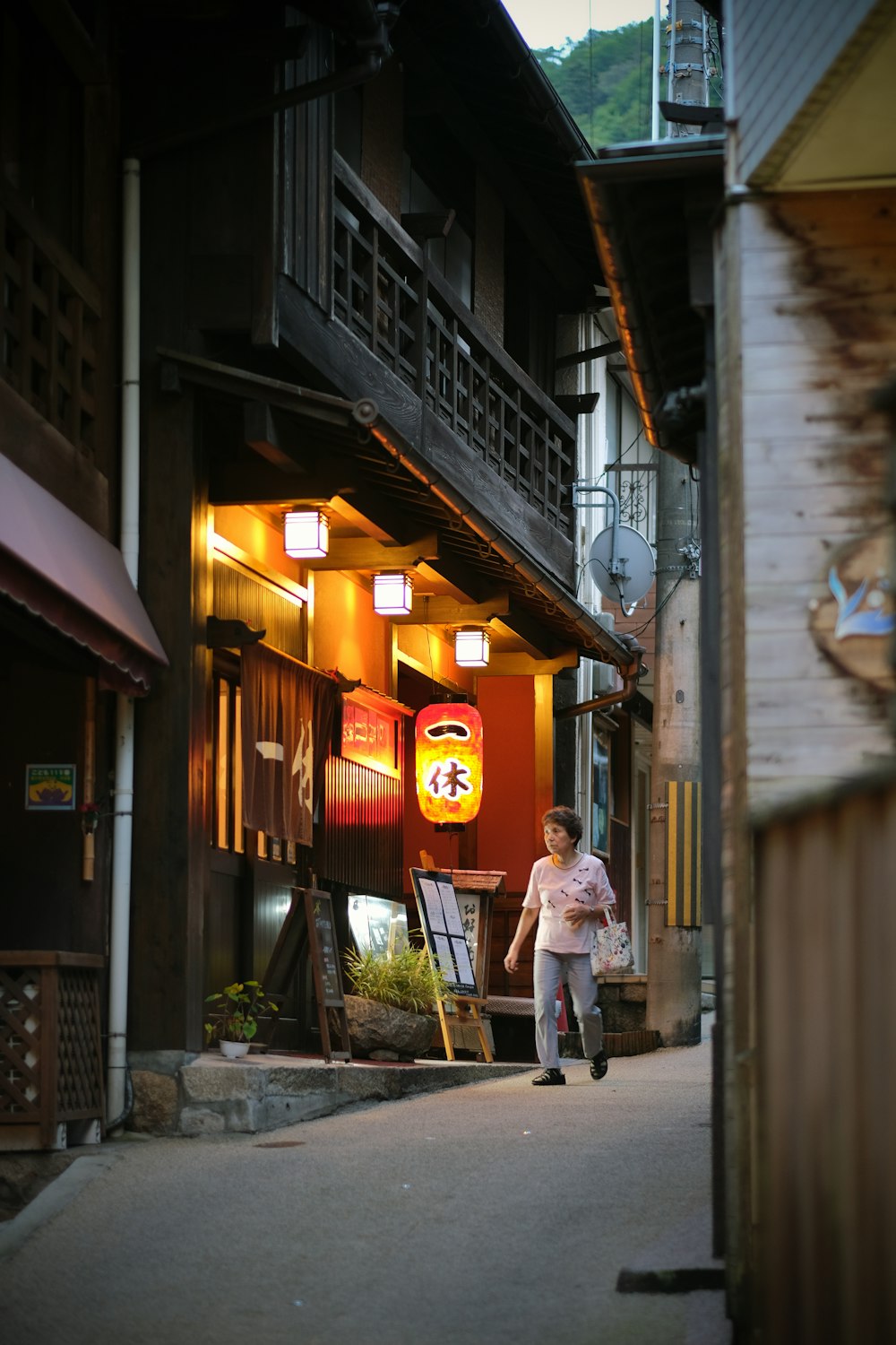 a woman walking down a street next to a tall building