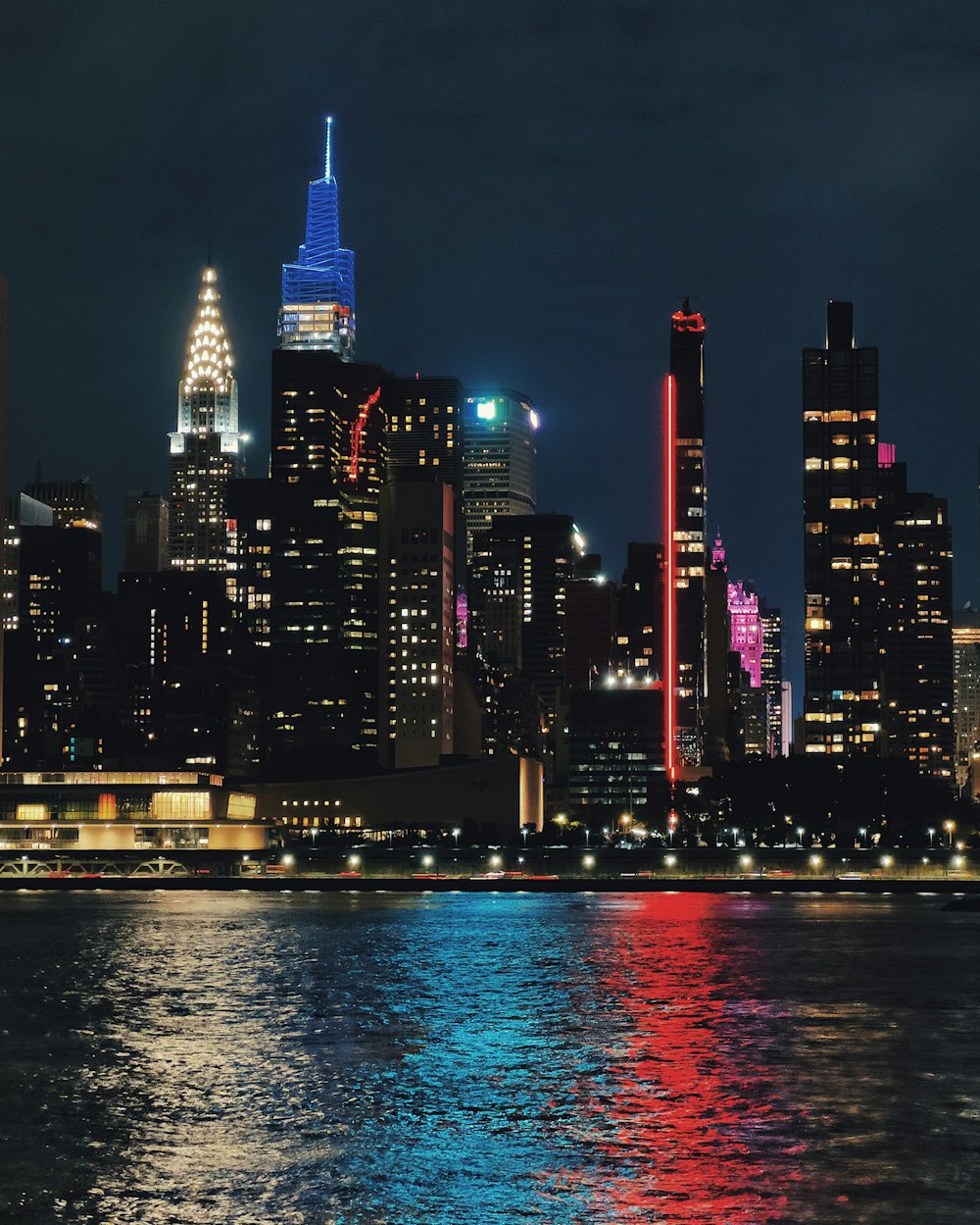 a city skyline at night with lights reflecting off the water