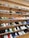 A variety of colorful sneakers neatly organized on several wooden shelves attached to a wall. The sneakers come in different designs and color combinations, showcasing a diverse collection suitable for display or sale in a retail environment.
