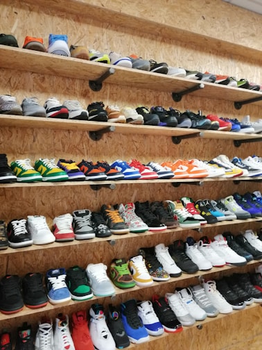 A vibrant display of colorful sneakers arranged on wooden shelves.