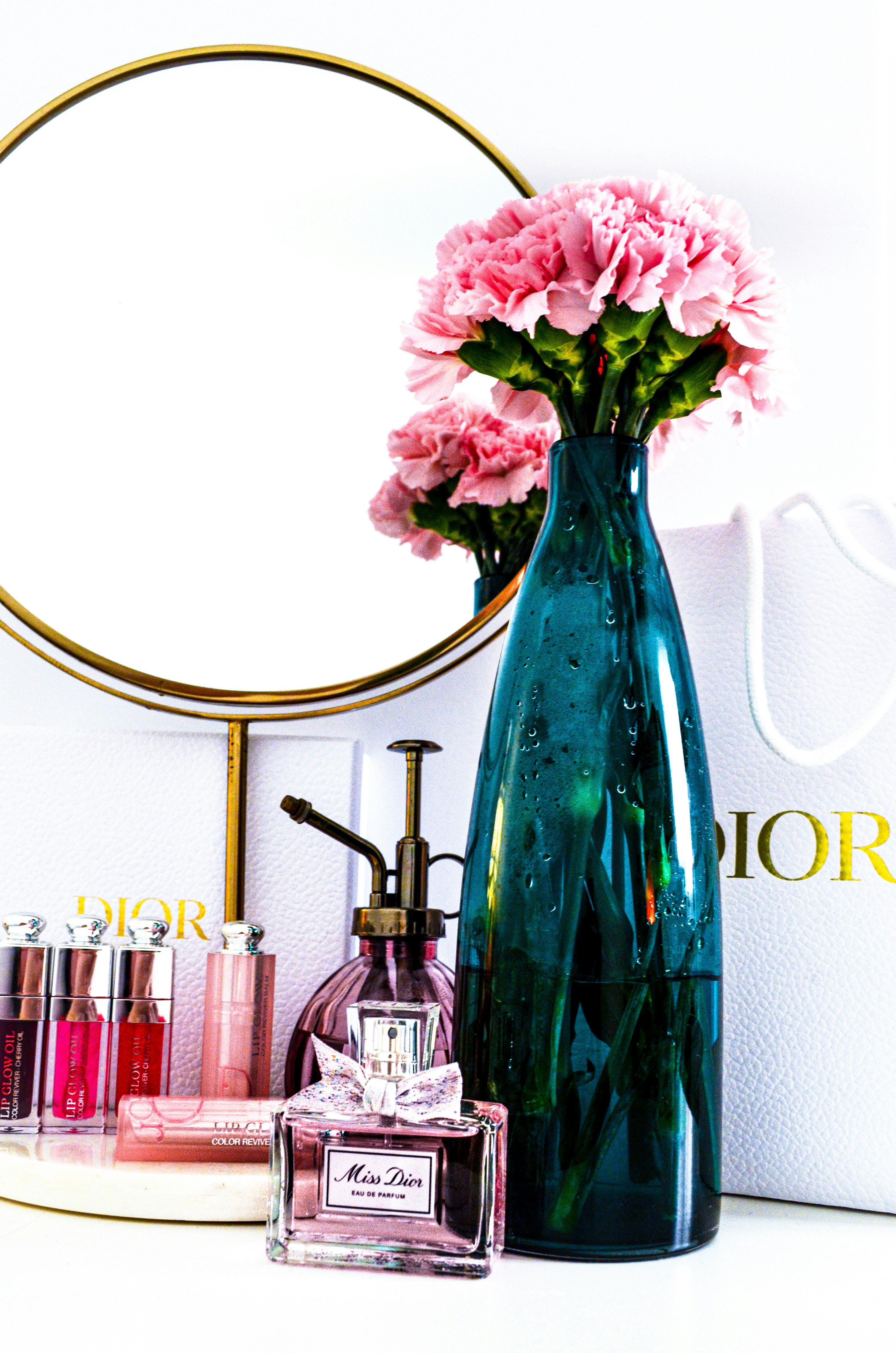 a vase with pink flowers sitting next to a mirror