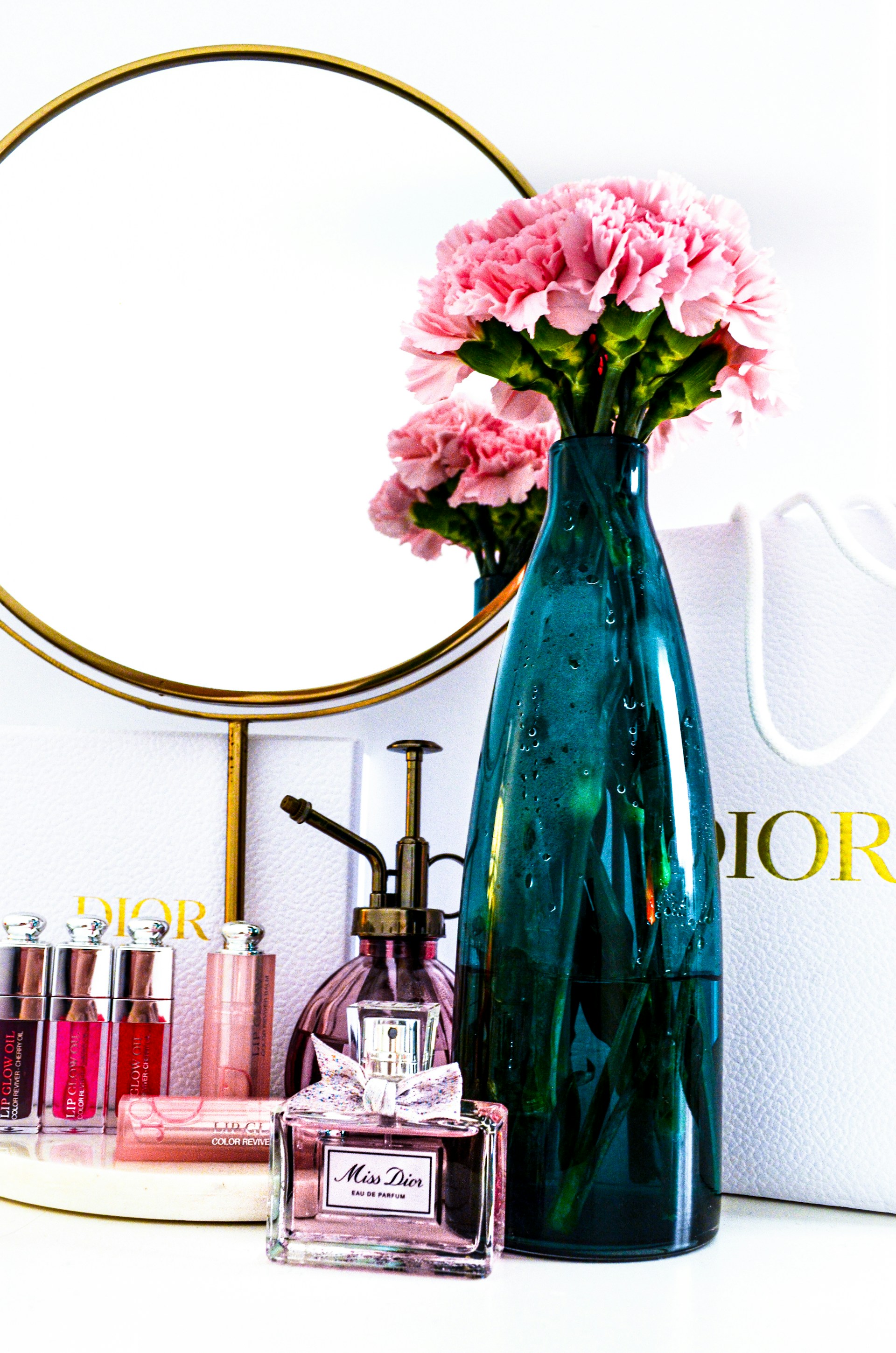 a vase with pink flowers sitting next to a mirror