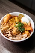 a bowl of food with noodles, meat, and vegetables