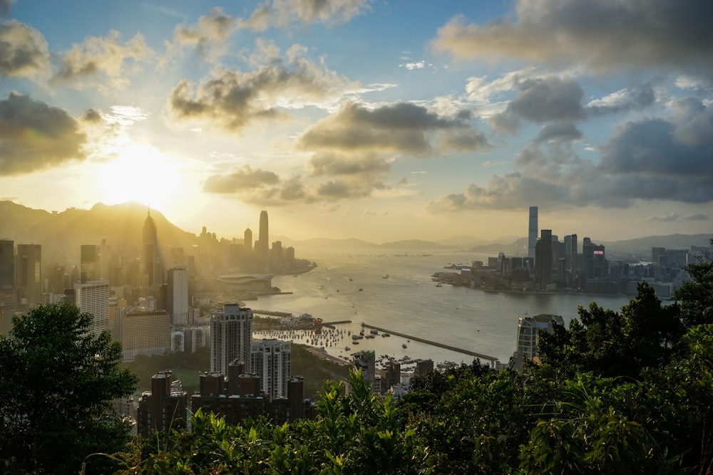 the sun is setting over a city and a body of water