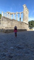 A child gazing in wonder at towering ancient ruins surrounded by jungle.