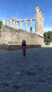 A child gazing in wonder at towering ancient ruins surrounded by jungle.