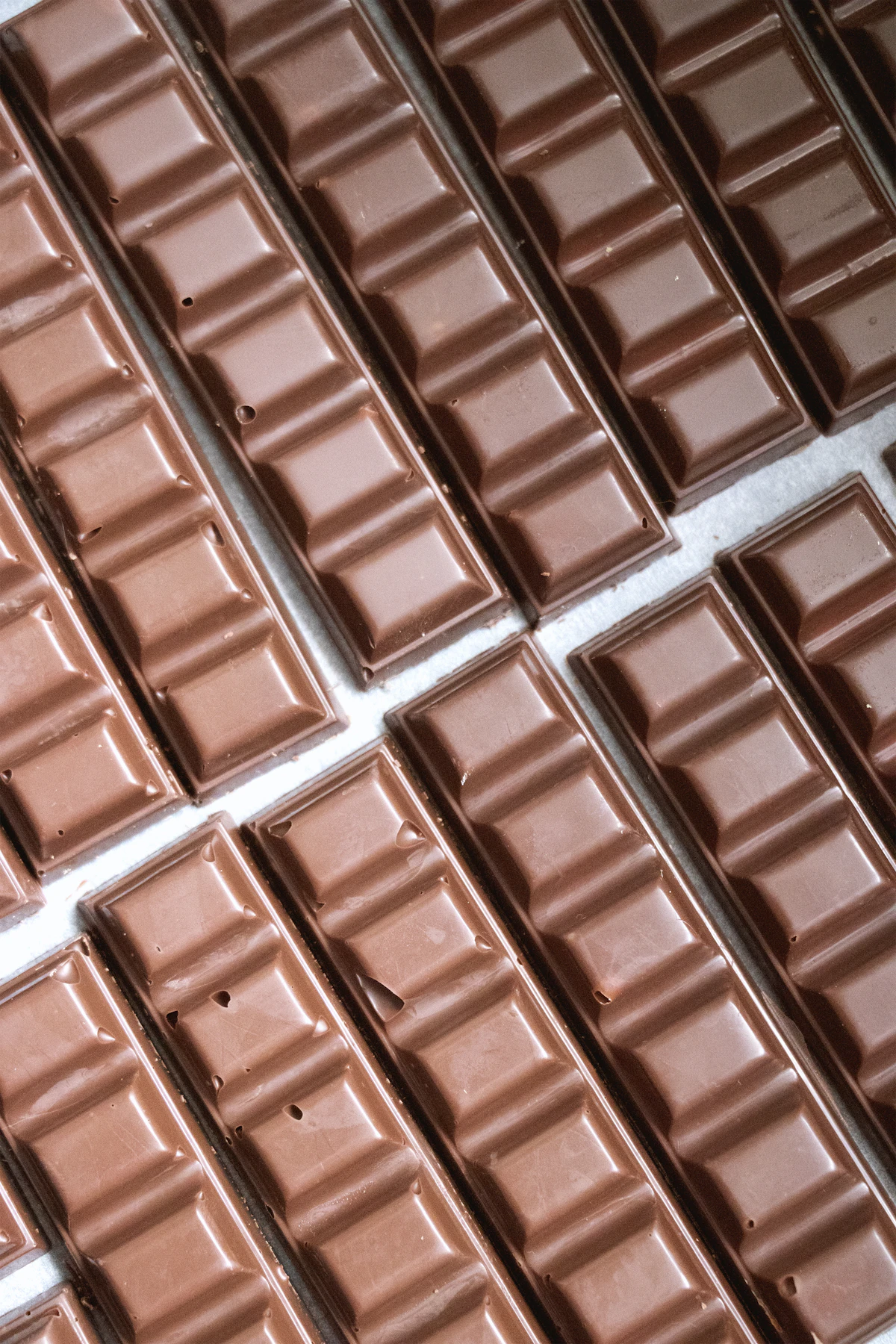 Varias tabletas de chocolate alineadas sobre una superficie clara.