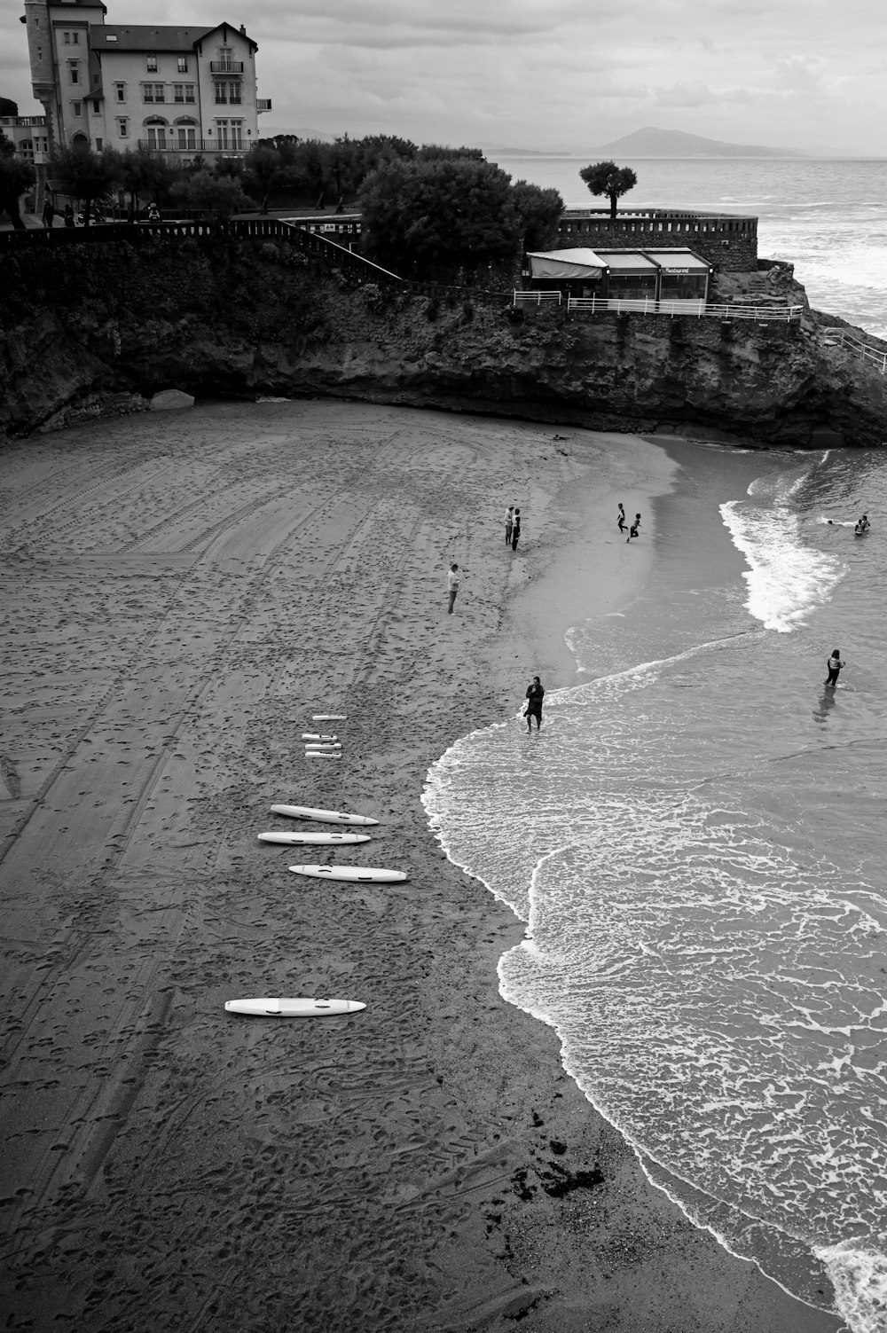 a group of people standing on top of a beach next to the ocean