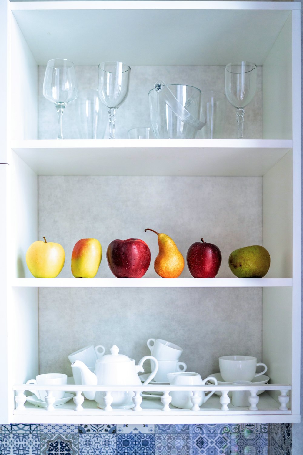 a shelf filled with glasses and fruit on top of it