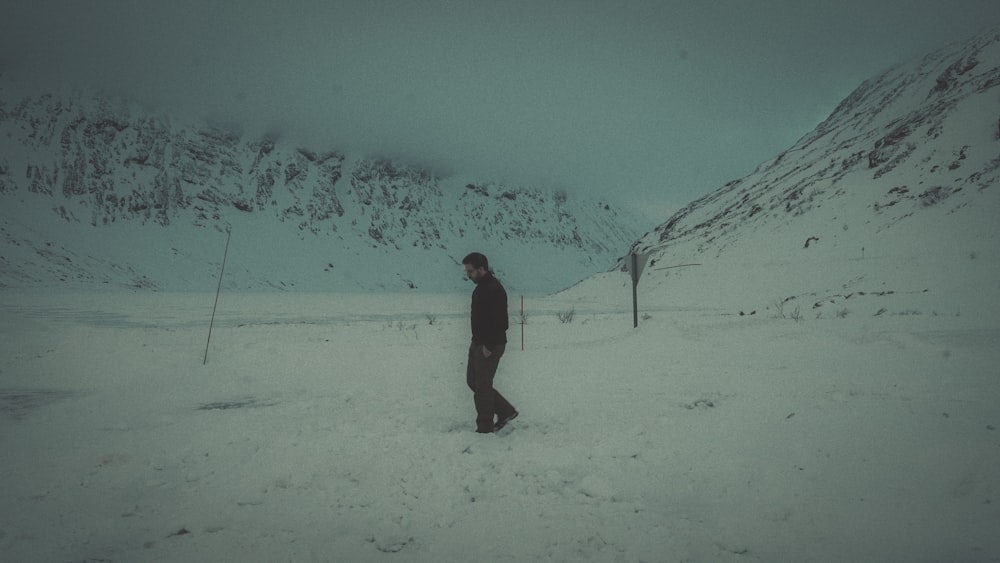 a man standing in the snow in front of a mountain