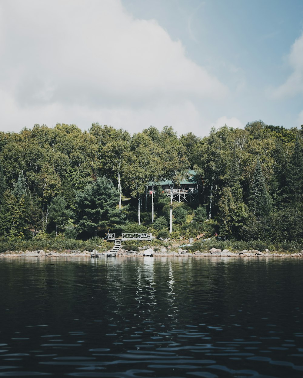 a house on the shore of a lake surrounded by trees