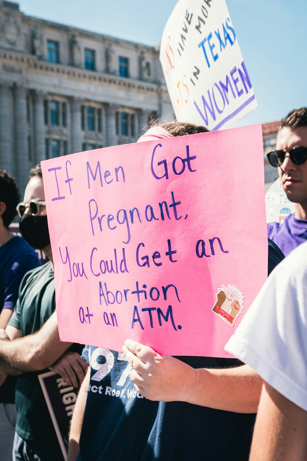 a man holding a pink sign that says if men got pregnant, you could get