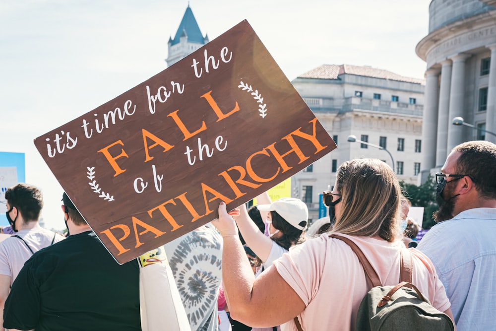 Eine Frau hält ein Schild, auf dem steht, dass es Zeit für den Fall der