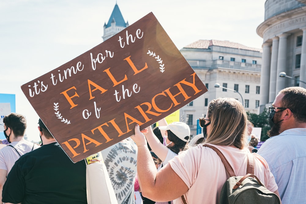 Una mujer sosteniendo un cartel que dice que es hora de la caída del
