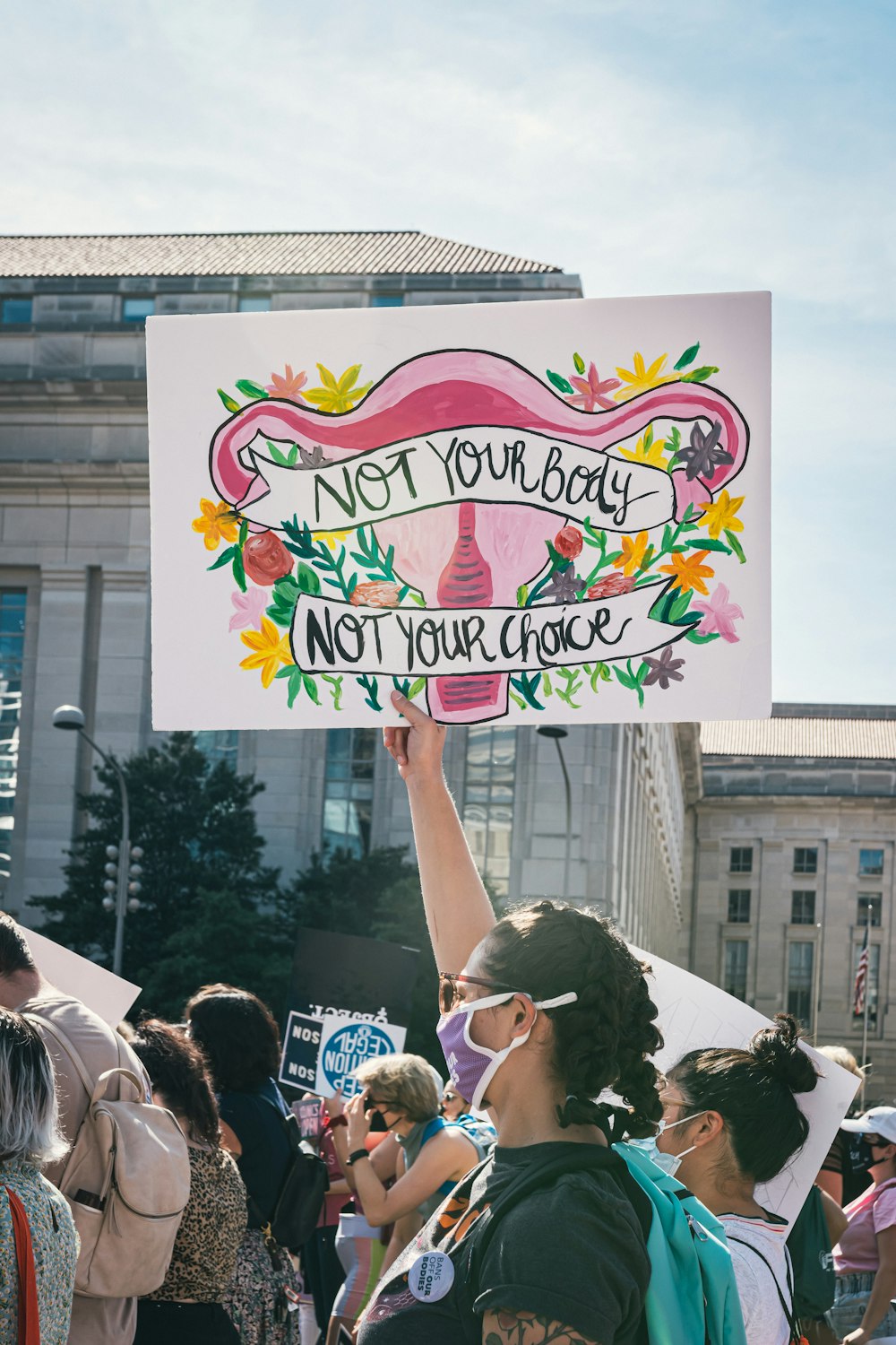 a woman holding a sign that says not your baby, not your choice