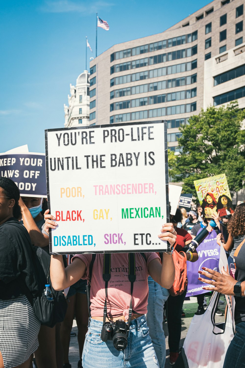 a woman holding a sign that says you're pro - life until the baby