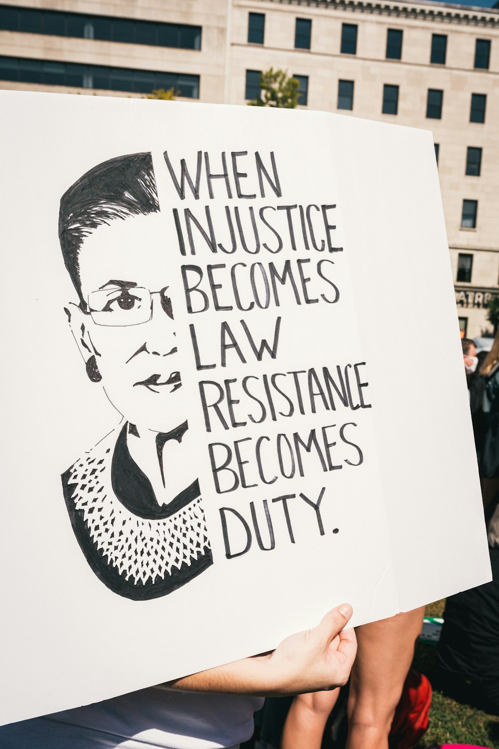 Eine Person, die ein Schild hält, das besagt, dass, wenn Gerechtigkeit Gesetz wird, Widerstand zur Pflicht wird