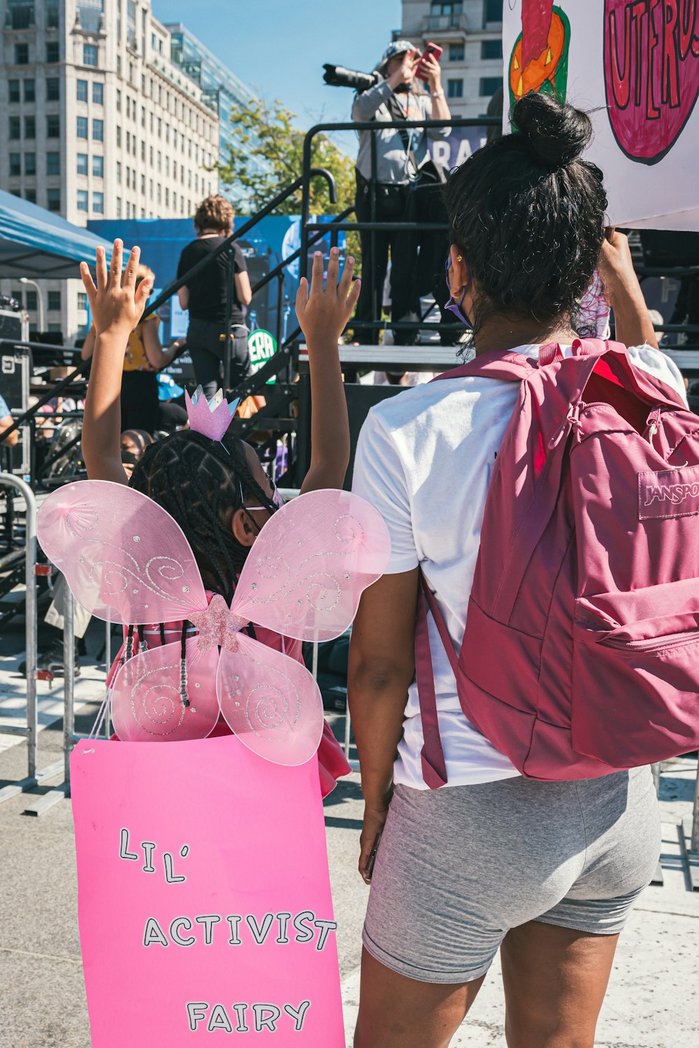 Una mujer con una mochila rosa sostiene un cartel
