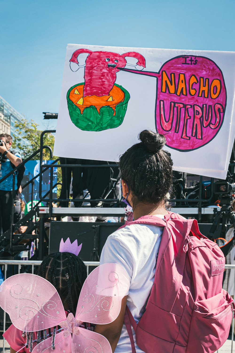 a woman in a pink backpack holding a sign