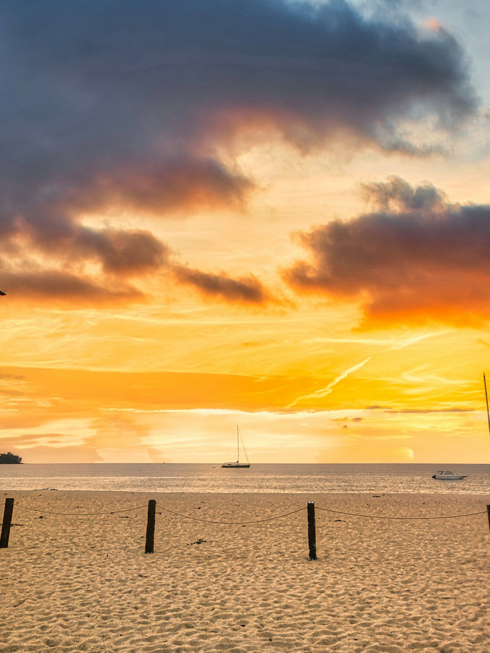 the sun is setting on the beach with boats in the water